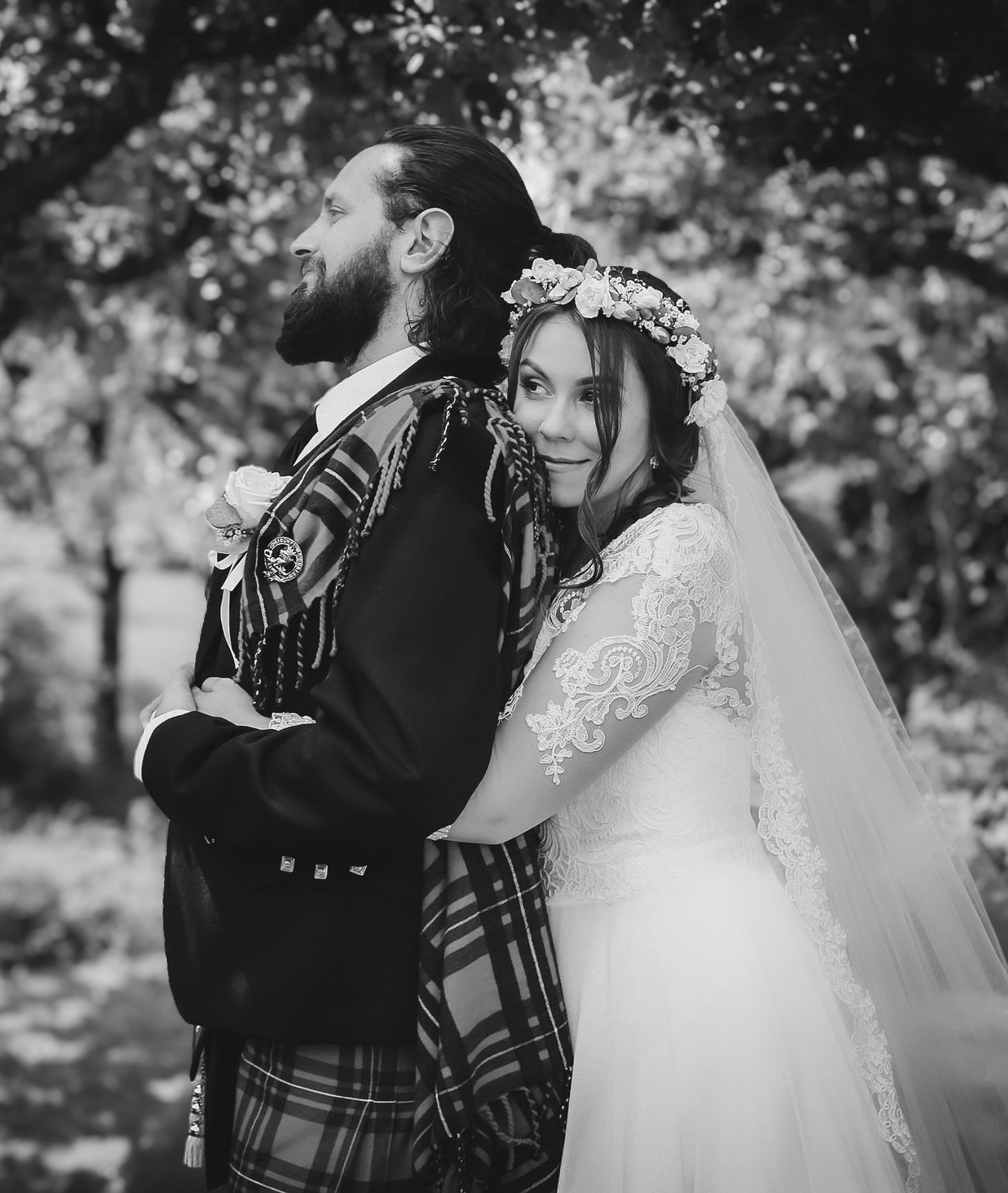 Black and white wedding photo showing a couple in traditional Scottish attire with the bride wearing a floral crown and veil.