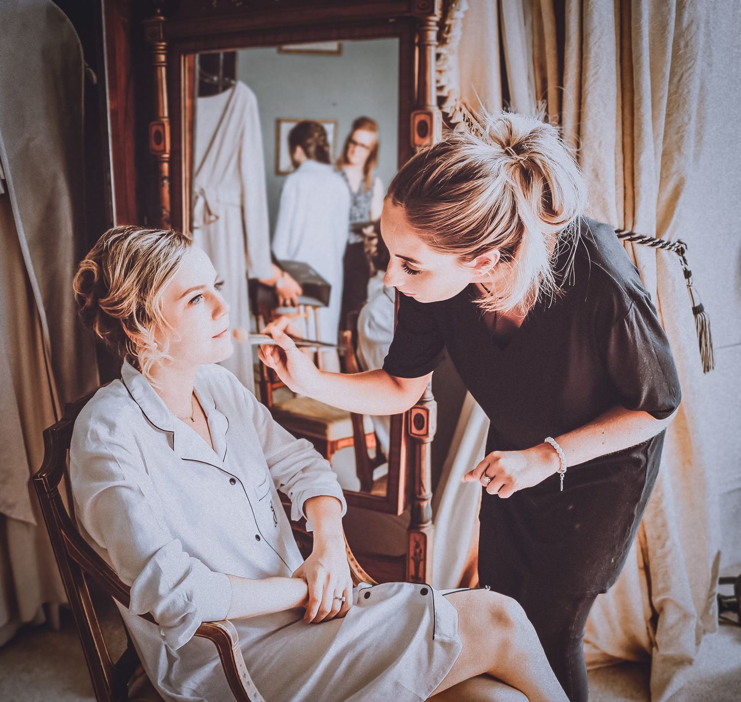 Professional makeup artist applying cosmetics while working in a dimly lit dressing room setting.